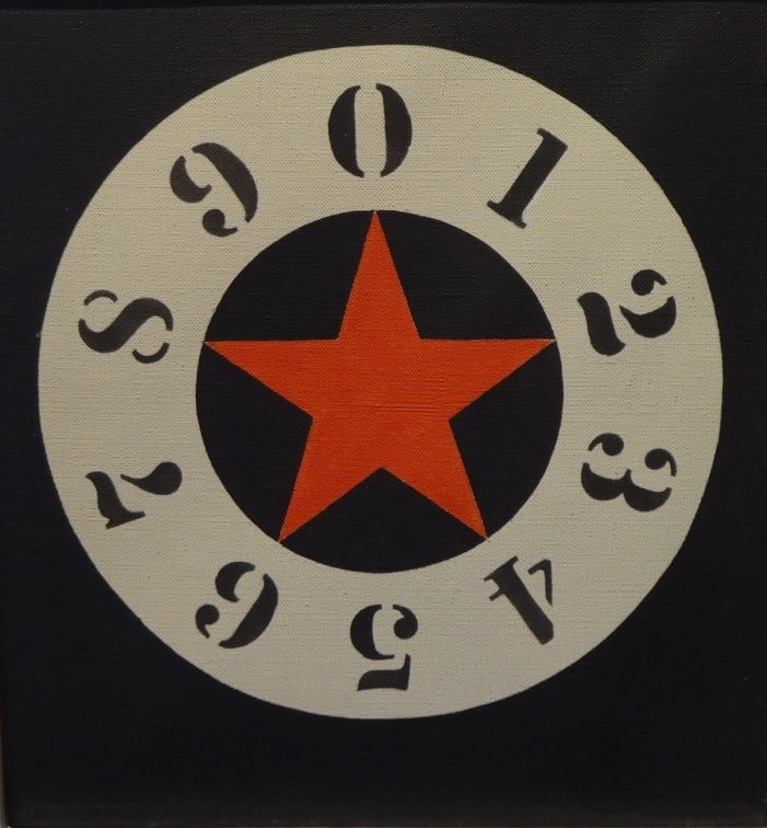 Untitled, a 12 by 11.25 inch canvas with a circle on a black background. In the middle of the circle is a red star. The star is surrounded by a white ring containing the black numerals going clockwise from zero at the top though nine.