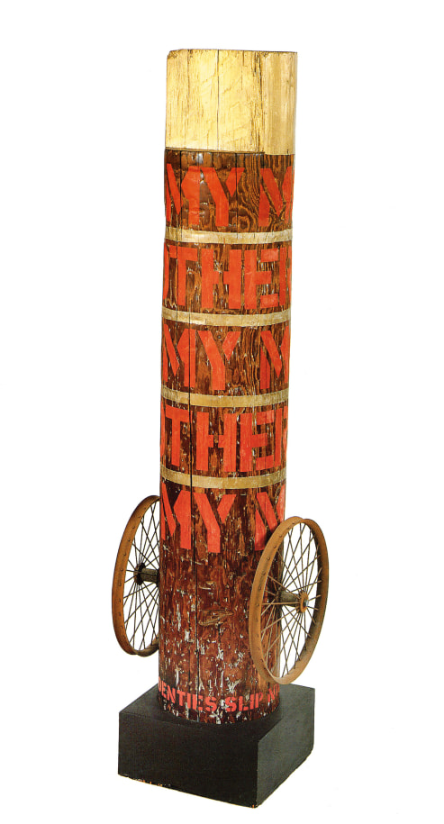 Column with its title &quot;My Mother&quot; painted in five rows around the column in red stenciled letters. The top of the column is painted gold, and thin gold strips around the column separate each row of text. At the bottom of the column, on both sides, is a wheel.