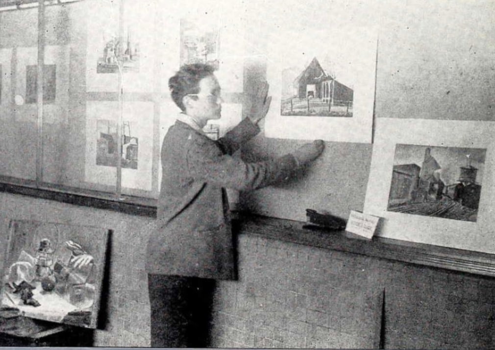 Robert Indiana hanging an exhibition of watercolors at Arsenal Technical High School, 1945