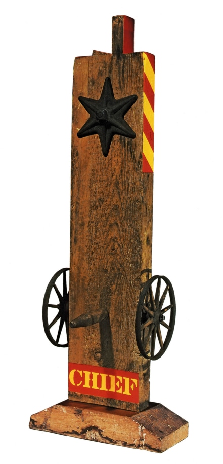 A 64 1/2 by 23 1/2 by 18 1/2 inch sculpture consisting of a wooden beam with a haunched tenon, and on a wooden base. The sculpture's title, &quot;Chief,&quot; is painted in yellow stenciled letters against a red rectangular ground across the bottom of the work. Above the title a wheel is attached to the right and left sides of the sculpture, and a wooden peg has been placed in the front of the sculpture, in between the wheels. At the top of the sculpture is a six pointed star. The top third of the right and sides of the sculpture are painted with diagonal red and yellow stripes, and the sides left and right sides of the tenon are painted red.