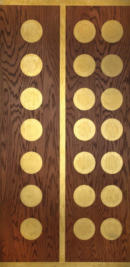 Twenty-one Golden Orbs, a painting of three vertical rows of seven golden orbs against a plywood background. A gold vertical stripe separates the first row of orbs from the second two. A golden stipe has also been painted on the bottom and top edges of the plywood.