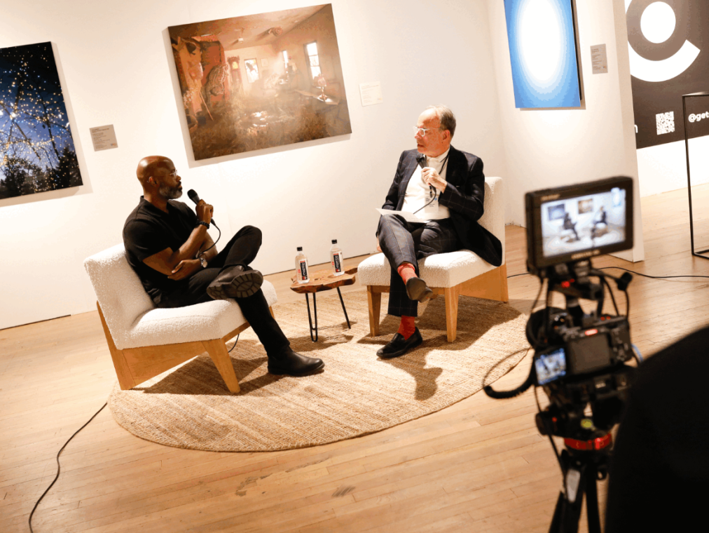 Two men sit in a lounge for an interview.