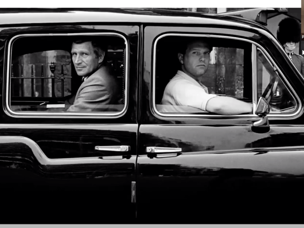 A screenshot of the Rodney Smith photograph John Hinch in Cab, London, England, 1987 which shows two men looking out a cab window in a black and white photograph. The screenshot includes the tiny thumbnail image of the speaker of the talk, Paul Martineau