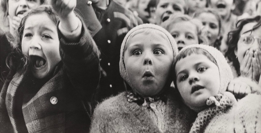 Black and white photo of children's faces as they react with excitement and astonishment.