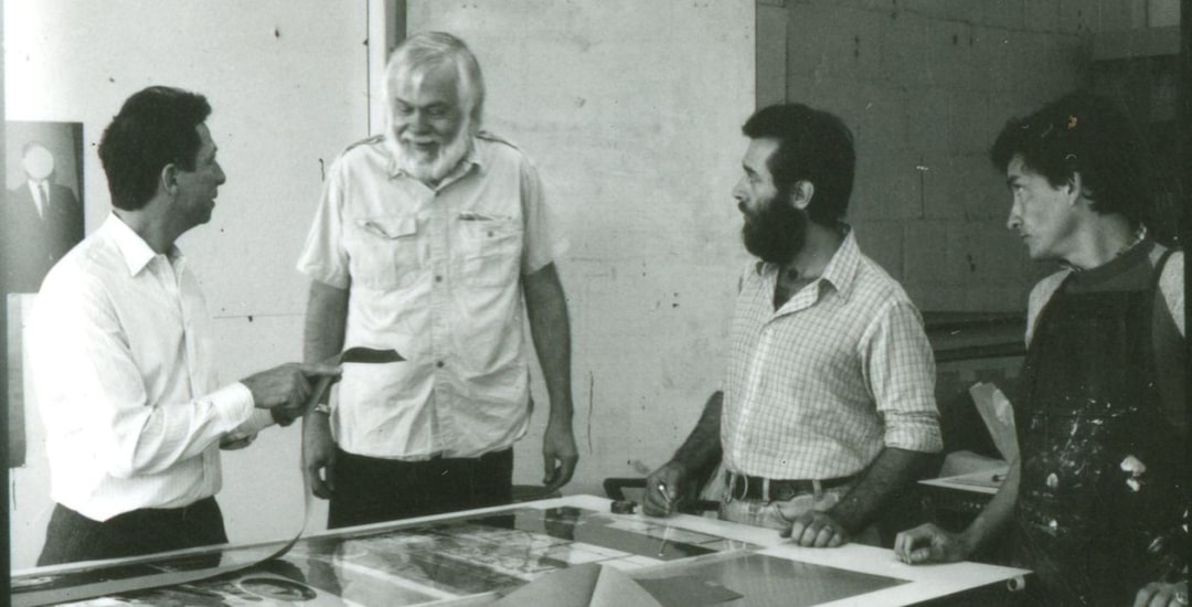 Click the banner to watch the full interview!, Image: Photo courtesy Cirrus Gallery, by Pablo Prietto; Cirrus founder Jean Milant, artist John Baldessari, and printers Richard Hammond and Francesco Siqueiros working at Cirrus Editions
