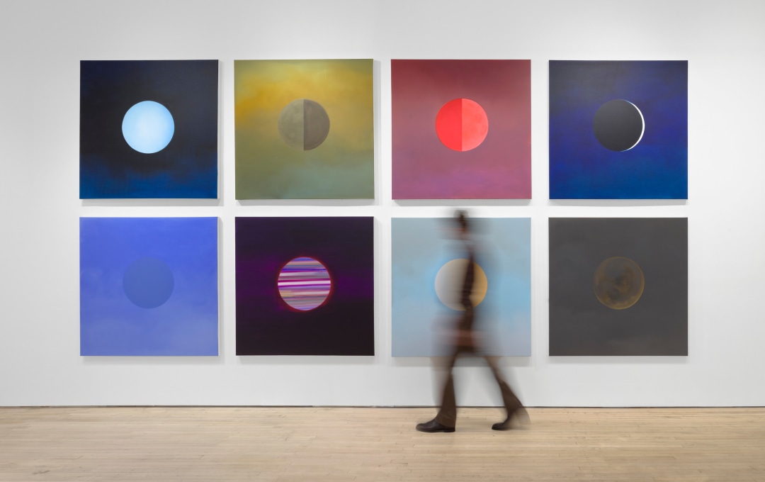 A painting of a neon yellow moon/sun against a grey sky