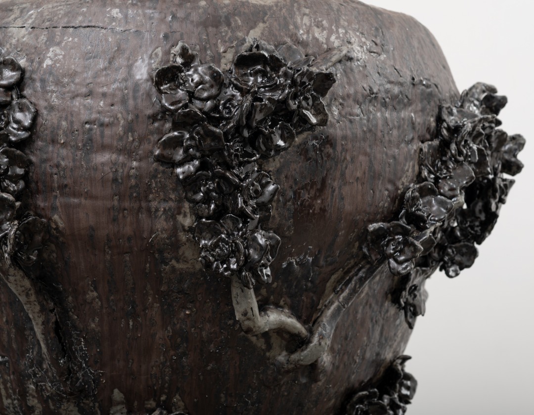 Detail of a sculpture by LaRissa Rogers of a ceramic floral vessel.