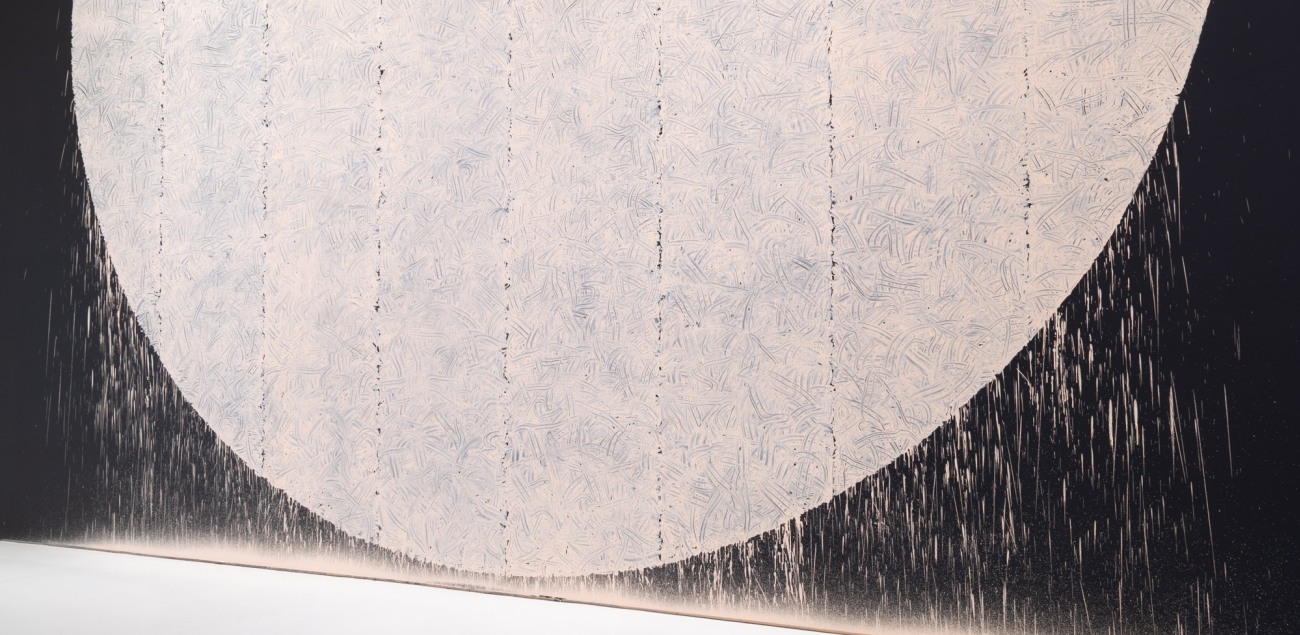 rectangular floor sculpture made up of pieces of flint rock with a vinyl wall text artwork in the background 