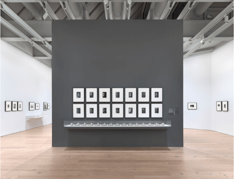Installation view of Working Together: The Photographers of the Kamoinge Workshop (Whitney Museum of American Art, New York, November 21, 2020–March 28, 2021). Left wall, from left to right: Anthony Barboza, Ming Smith, NYC, 1973; Al Fennar, Sag Harbor, 1975; Al Fennar, Straight Street, 1965; Herb Robinson, Relaxing in Central Park, 1961; Herb Robinson, The Girls, 1969; Ming Smith, Sun Breeze after the Bluing, Hoboken, New Jersey, c. 1972; Ming Smith, Kites Inside, Columbus, Ohio, c. 1972. Middle wall, clockwise from top left: Anthony Barboza, Self Portrait (Anthony Barboza), 1972; Anthony Barboza, Adger Cowans, 1972; Anthony Barboza, Dan Dawson, 1972; Anthony Barboza, Louis Draper, 1972; Anthony Barboza, Al Fennar, 1972; Anthony Barboza, Ray Francis, 1972; Anthony Barboza, Herman Howard, 1972; Anthony Barboza, Calvin Wilson, 1972; Anthony Barboza, Shawn Walker, 1972; Anthony Barboza, Ming Smith, 1972; Anthony Barboza, Beuford Smith, 1972; Anthony Barboza, Herb Robinson, 1972; Anthony Barboza, Herbie Randall, 1972; Anthony Barboza, Jimmie Mannas, 1972; Vitrine: Anthony Barboza, Kamoinge Artists’ Book, 1972. Right wall, from left to right: C. Daniel Dawson, Grandma Thomas, 1968; Shawn Walker, Boy with Banana by the Window, Bronx, NY, 1966; Shawn Walker, Harlem, 117th Street, c. 1960. Photograph by Ron Amstutz