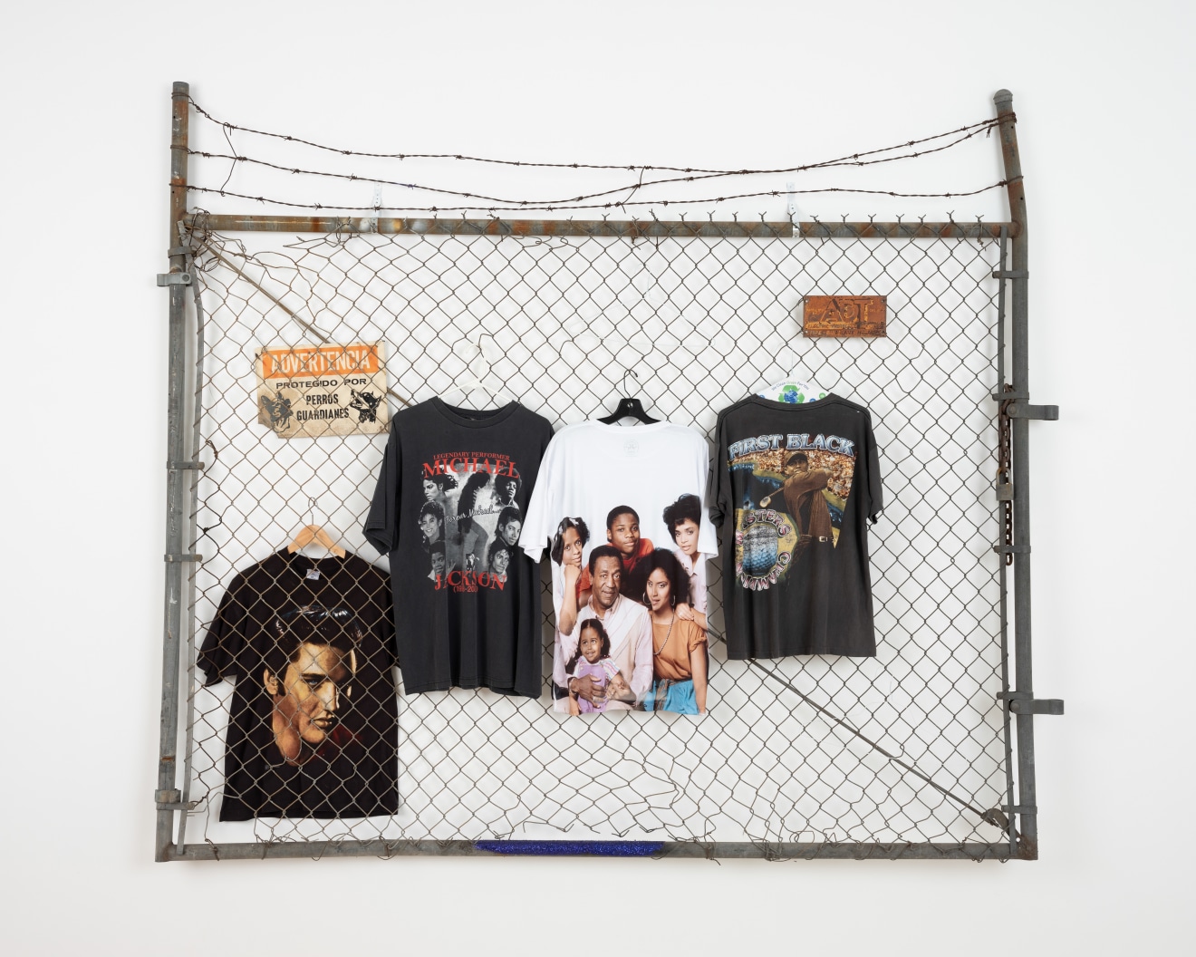 So many clothes I ran out of hangers (Black,&nbsp;White &amp;amp; Grass),&nbsp;2019, Metal fence with barbed wire, assorted tees on hangers