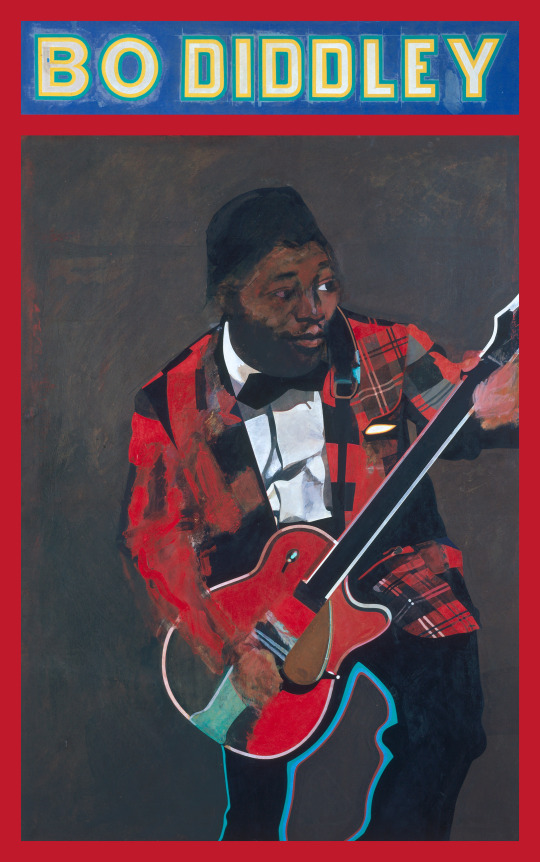 Man playing guitar wearing red plaid blazer, with "Bo Diddley" written across top of board