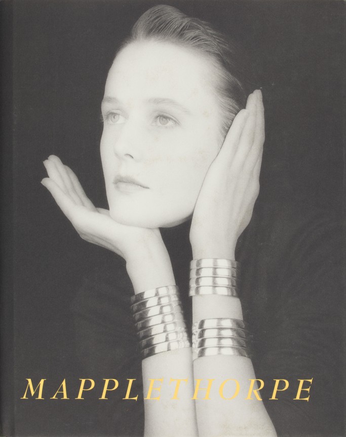 Portrait of Lucy Ferry wearing silver cuff bracelets  with her hands around her face.