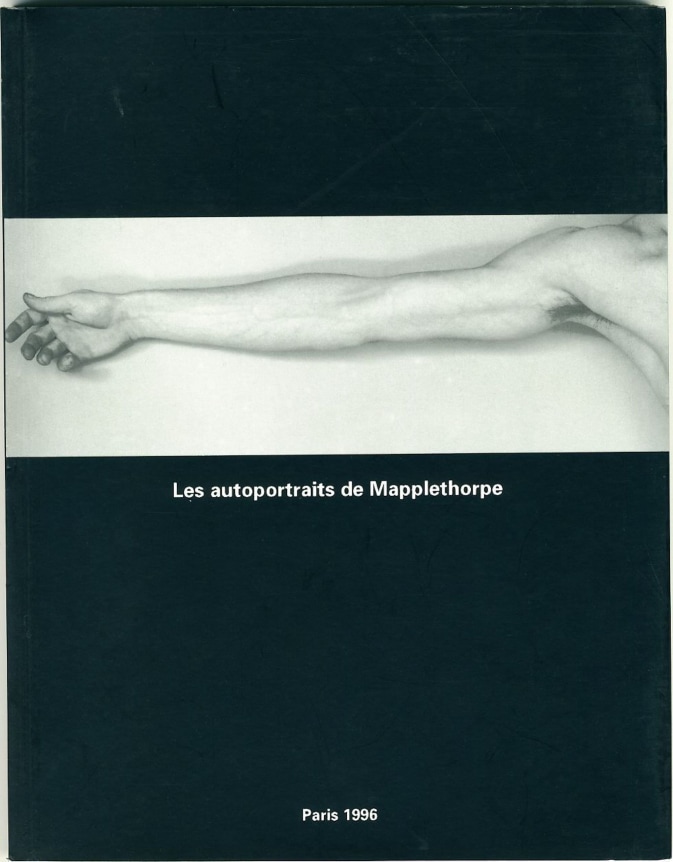 Self-portrait of outreached arm on black background with white text.