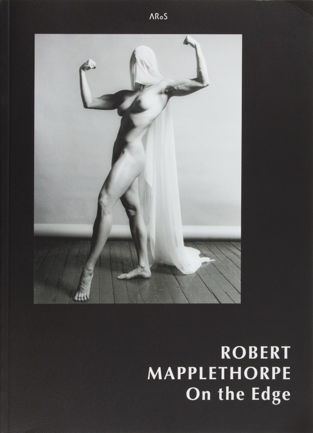 Lisa Lyon veiled in gauze flexing her muscles, white text on black background.