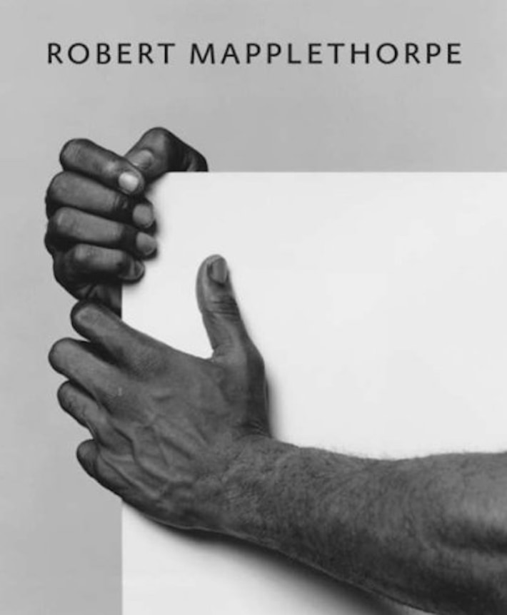 The arms of a a black man resting on a pedestal holding a white square