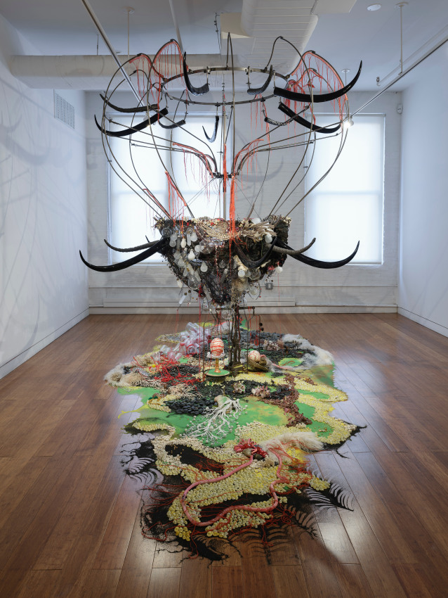 Rina Banerjee,&nbsp;A world Lost: after the original island, single land mass fractured, after populations migrated, after pollution revealed itself and as cultural locations once separated merged, after the splitting of Adam and Eve, Shiva and Shakti, of race black and white, of culture East and West, after animals diminished, after seas&rsquo; corals did exterminate, after this and at last imagine all water evaporated&hellip;this after Columbus found it we lost it imagine this,&nbsp;2013,&nbsp;Black synthetic horns, wire, netting, lightbulbs, scale, ostrich eggs, textiles, cowrie shells, pebbles, coins, feathers, fish vertebrae, greenery, coral, glass birds, miniature human and animal figurines, plastic cups, and red thread, 132 x 234 x 128 in.&nbsp;