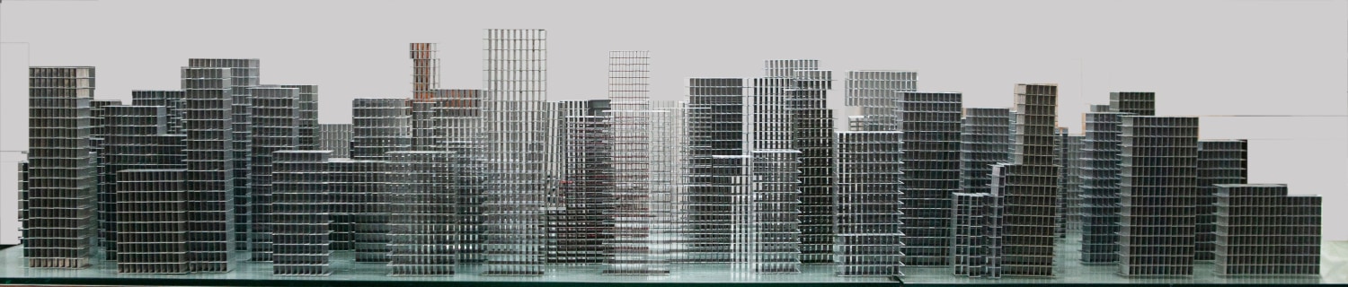 Sculptural cityscape made from cement pins displayed atop a mirror.