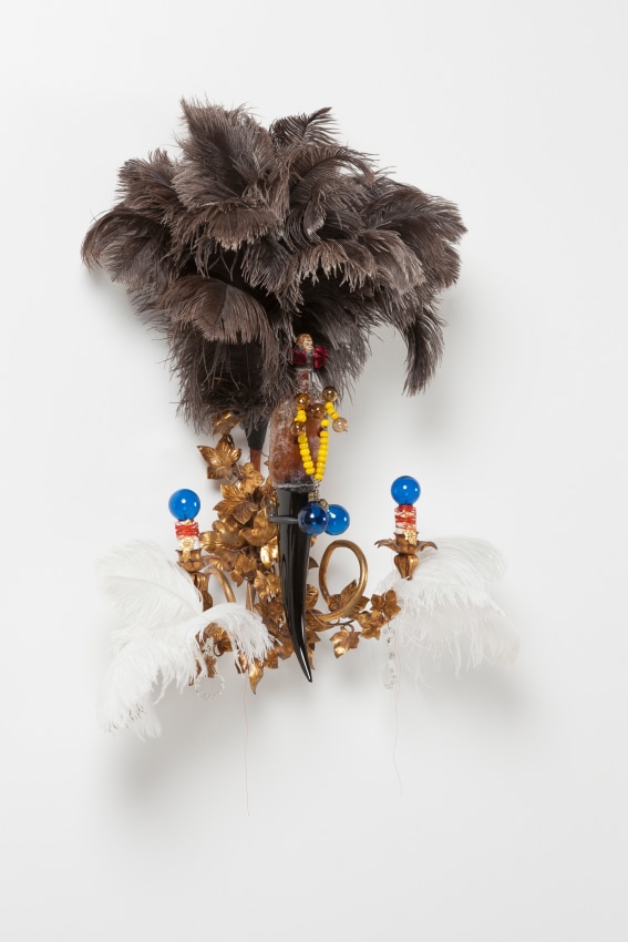 Rina Banerjee,&nbsp;Sex-bait, in likeness to fish bait to catch her as disloyal, in likeness to Eve, arouse her fear, to create racial panic of blacks jewels like honey to stir and stir poison n&#039; passion, minted lynchings in likeness to money,&nbsp;2017,&nbsp;Ceramic vintage negro head, Victorian brown bitters bottle, red silk tassels, Murano glass, and steel armature,&nbsp;34 x 23 x 13 in