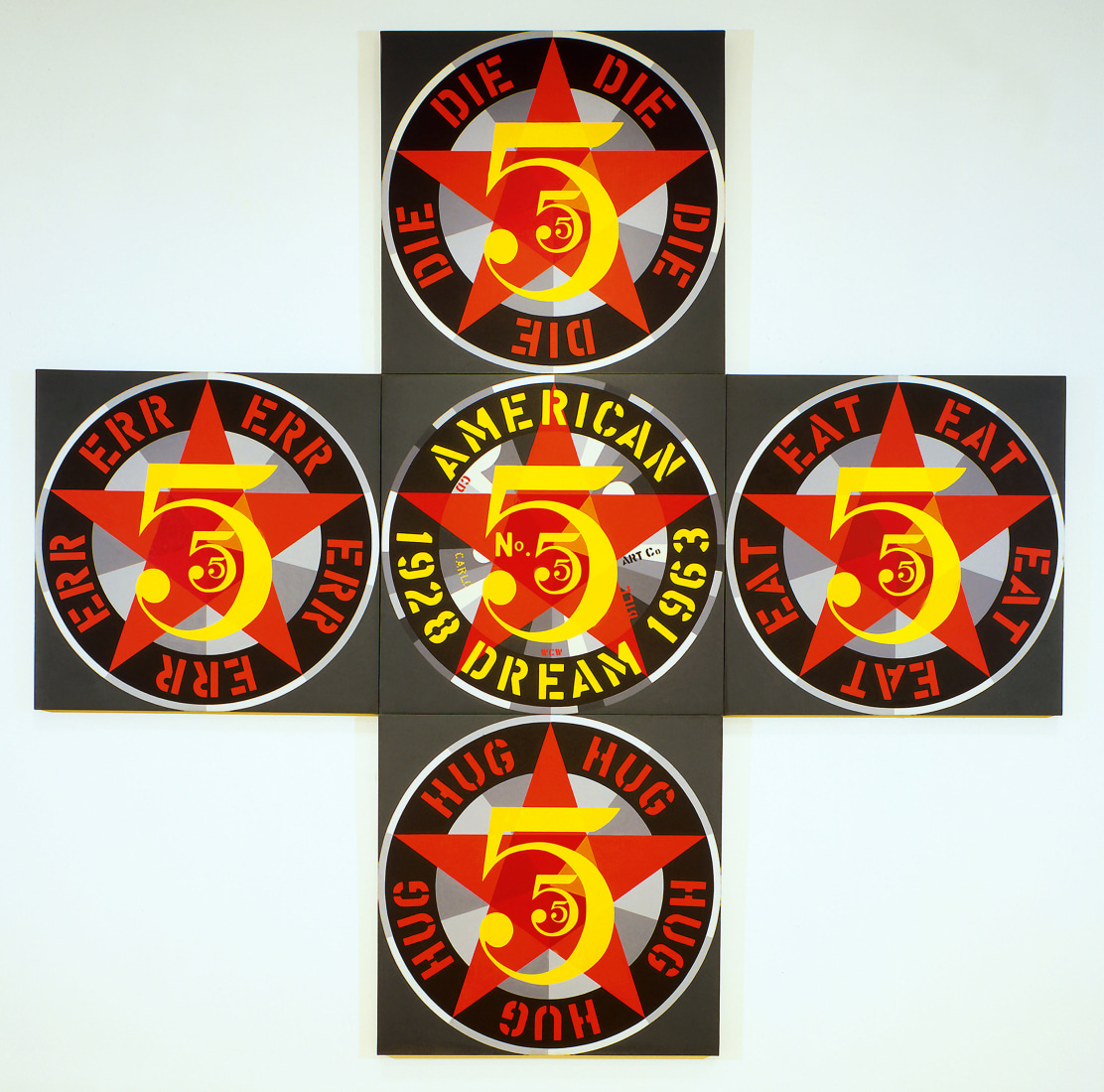 The Demuth American Dream No. 5, a cross shaped painting made up five panels. Each panel has a dark gray ground and holds a three yellow number fives in three sizes against a red star. Each panel has a black ring of text around the fives. The central ring has the text American Dream and the dates 1928 and 1963 in yellow. Each other ring contains a word painted in red which appears five times, in between each arm of the star. The word in the top panel is DIE, in the right panel it's EAT, in the lower panel HUG, and in the left panel ERR