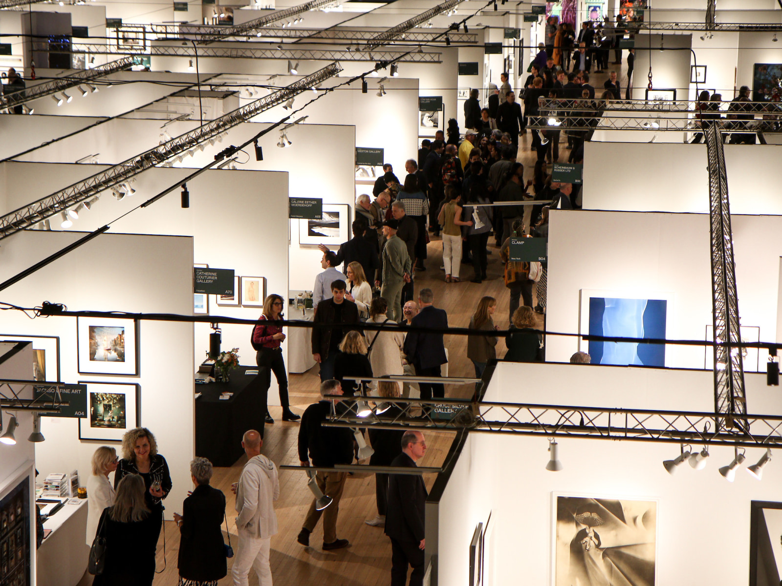 A crowded aisle shows attendees of The Photography Show 2024 from a bird's eye view above.