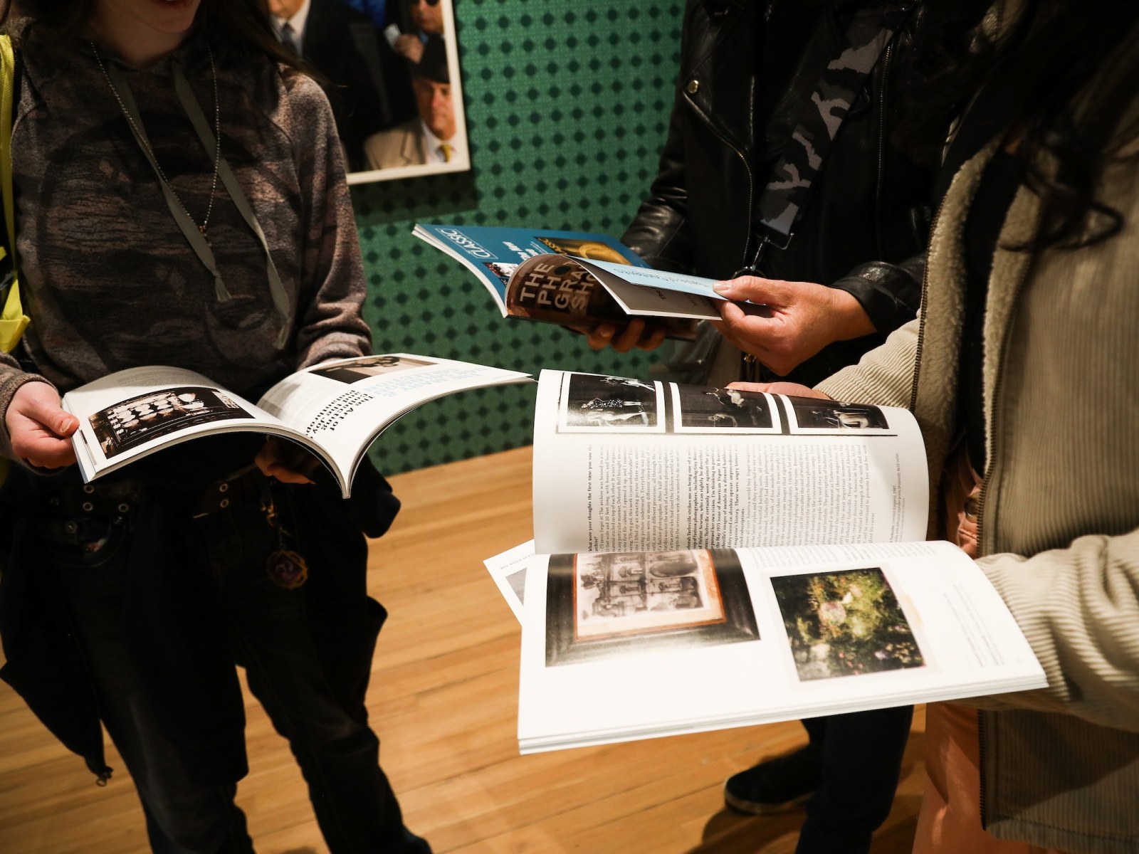 Three people look at the catalogue for The Photography Show.