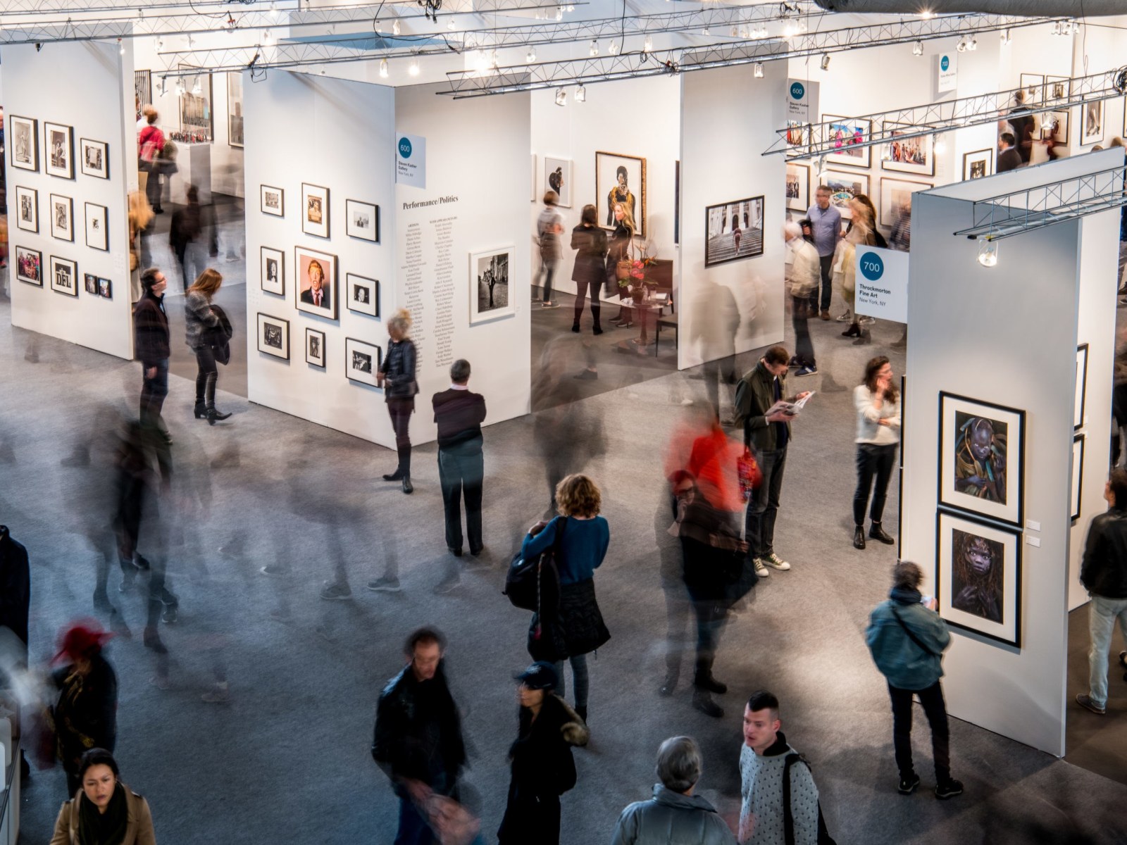 A time-lapse photo of people walking through the aisles of The Photography Show.