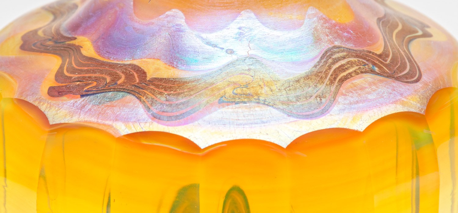 a detail of an original blown tiffany favrile glass vase from the late 1890s, showing iridescent wave and scrolling motifs