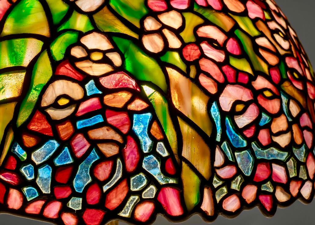 the tiffany begonia lamp shade in detail, showing the different shades of pink, green, and the mottling of the glass and various textures used to create the image of begonia flowers