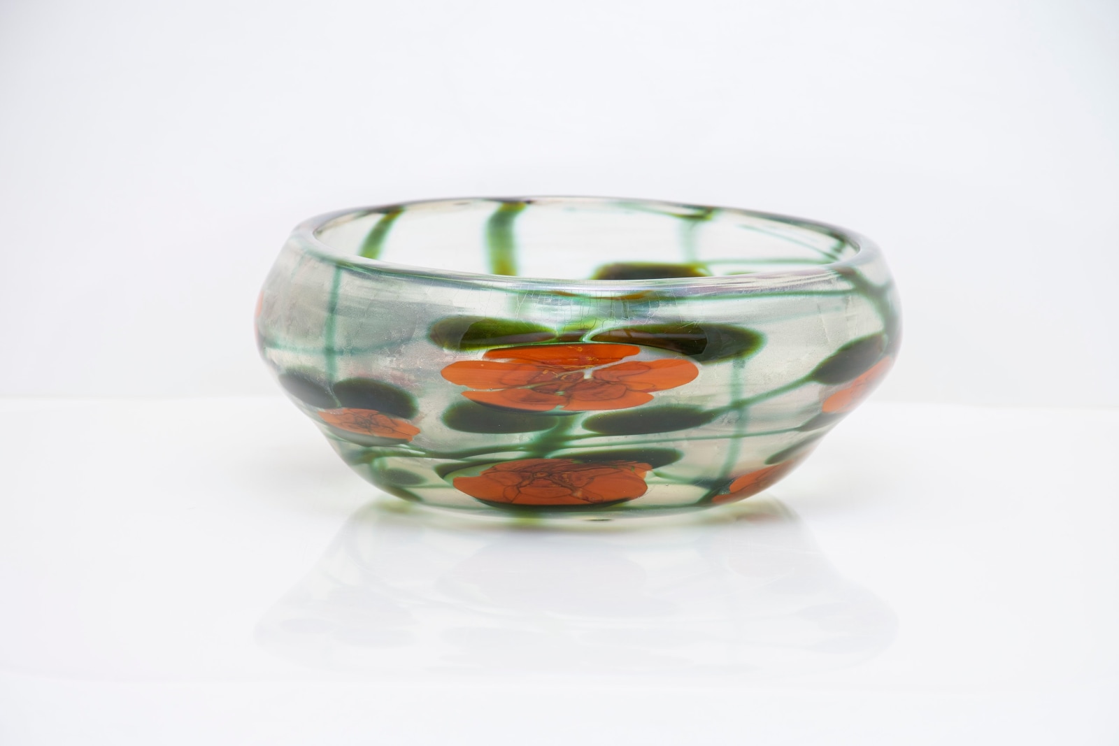 a tiffany favrile glass paperweight vase, the clear low wide body with iridescent interior, decorated with red nasturtium flowers surrounded by large round green leaves and swirling vines.