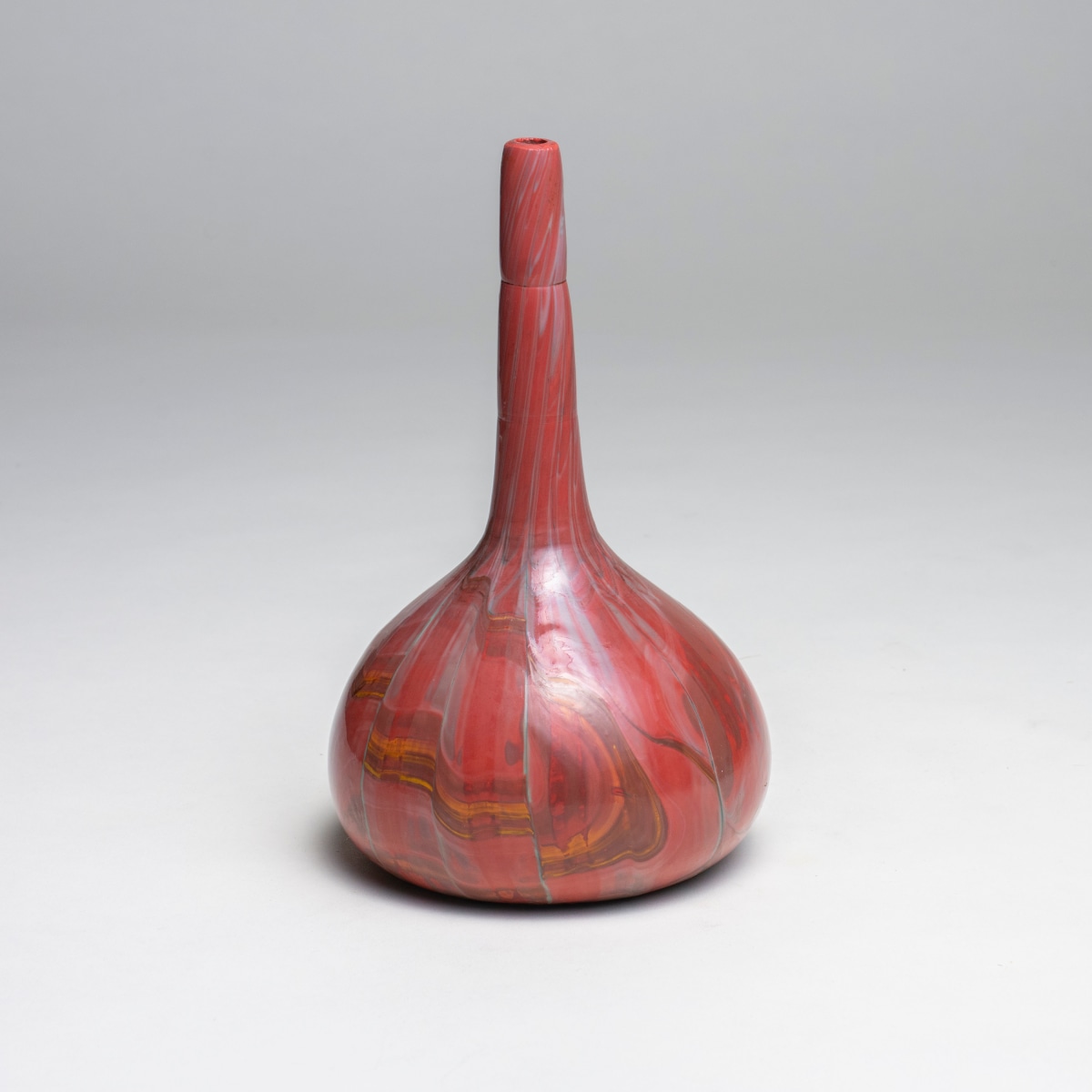 an early tiffany favrile glass vase, bottleneck form, the glass made to look like striated stone, this vase in shades of red with orange and rusty brown tones with occasional light blue highlights.