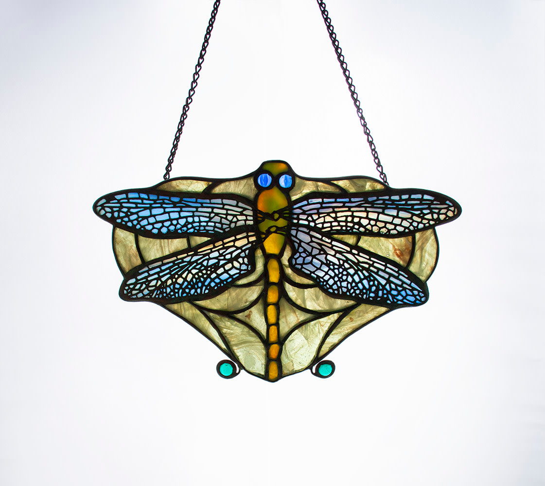 a lamp screen for a tiffany lamp, made by tiffany studios around 1906, a leaded glass dragonfly in translucent glass designed to hang from a chain to block early light bulbs which were seen as too harsh