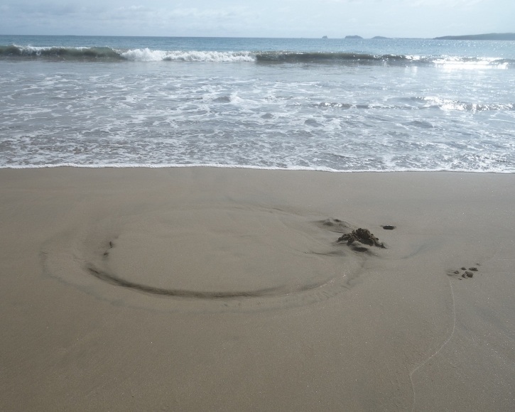 Large circle in the sand and a hole in the sand where the woman was kneeling.