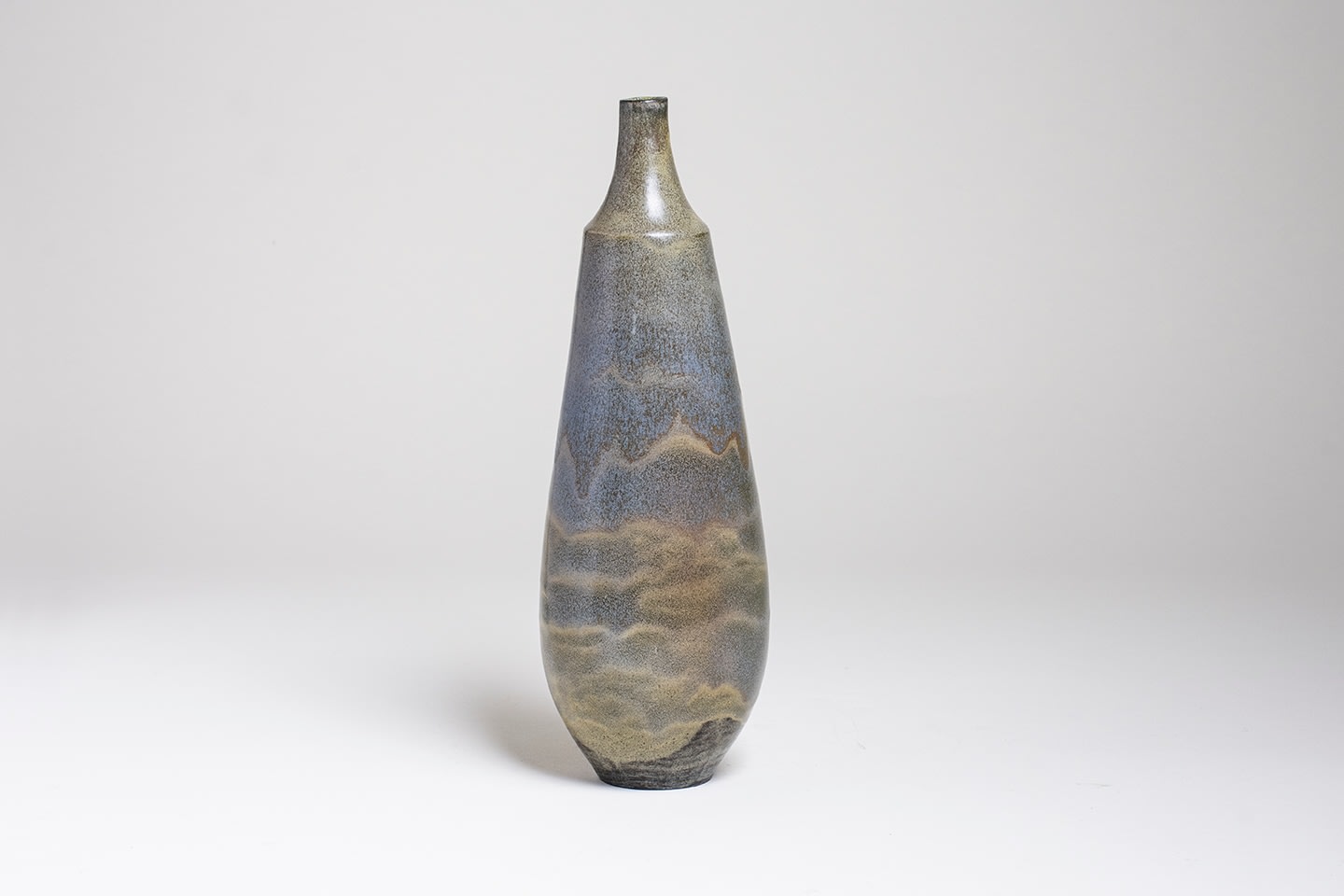 a tall thin bottle form vase by gertrud and otto natzler, the simple form accented by the glaze, a dripping gray blue Mariposa reduction fired glaze