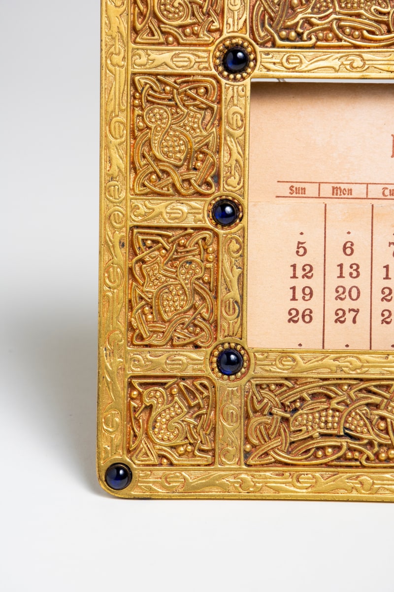 detail of the calligraphic animals in the gilt bronze calendar frame from the tiffany studios 9th century desk set, also showing the blue Tiffany favrile glass jewels