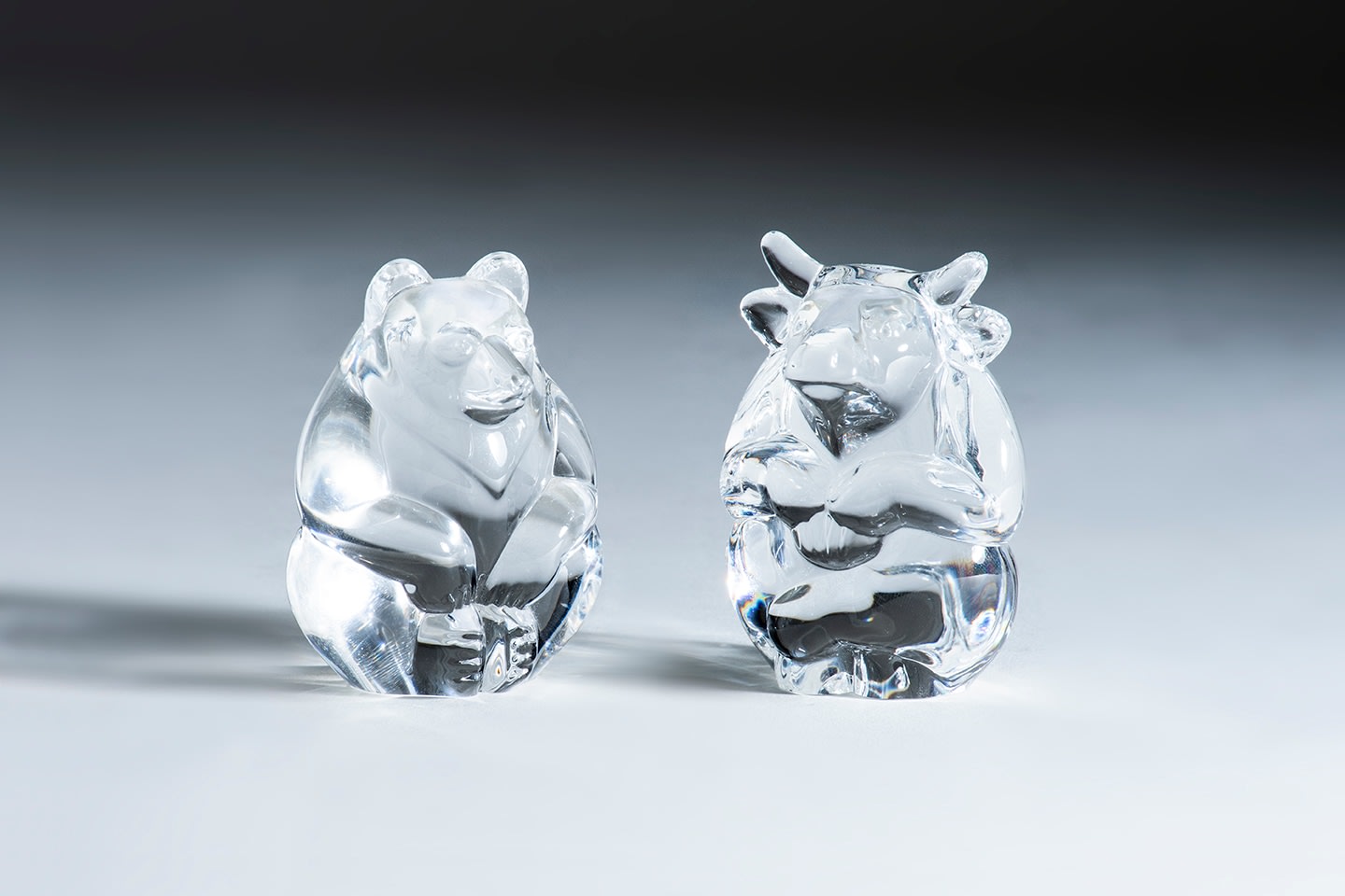 small ovoid crystal sculptures meant to nestle in the palm of the hand, one in the form of a bear and the other a bull