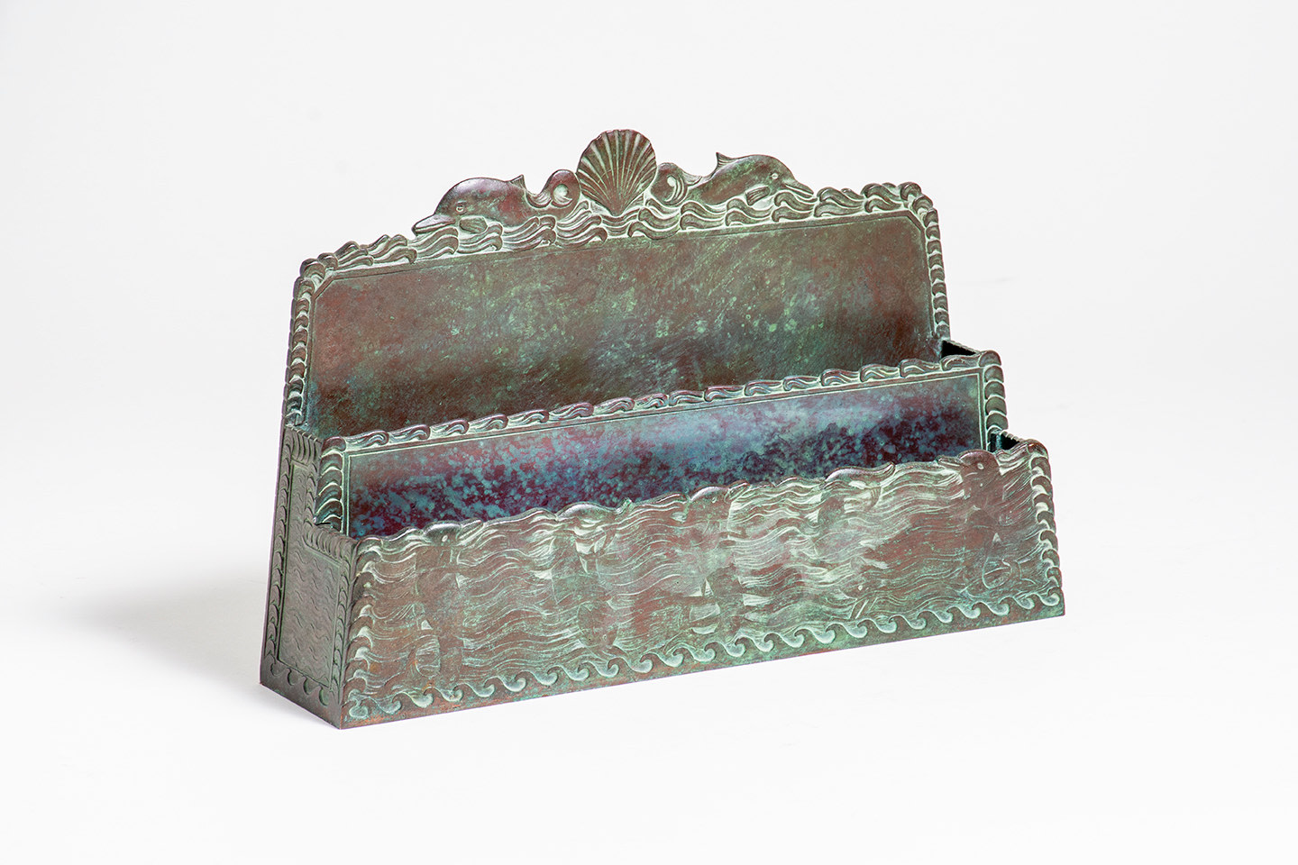 a paper rack from tiffany studios' Nautical desk set, depicting wavy water with dolphins diving and swimming, with a scallop shell and two dolphins on the back panel