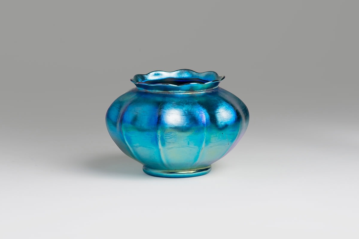A blue iridescent Tiffany Favrile Glass vase, the rounded pillowed body with subtle vertical ribbing and ruffled rim