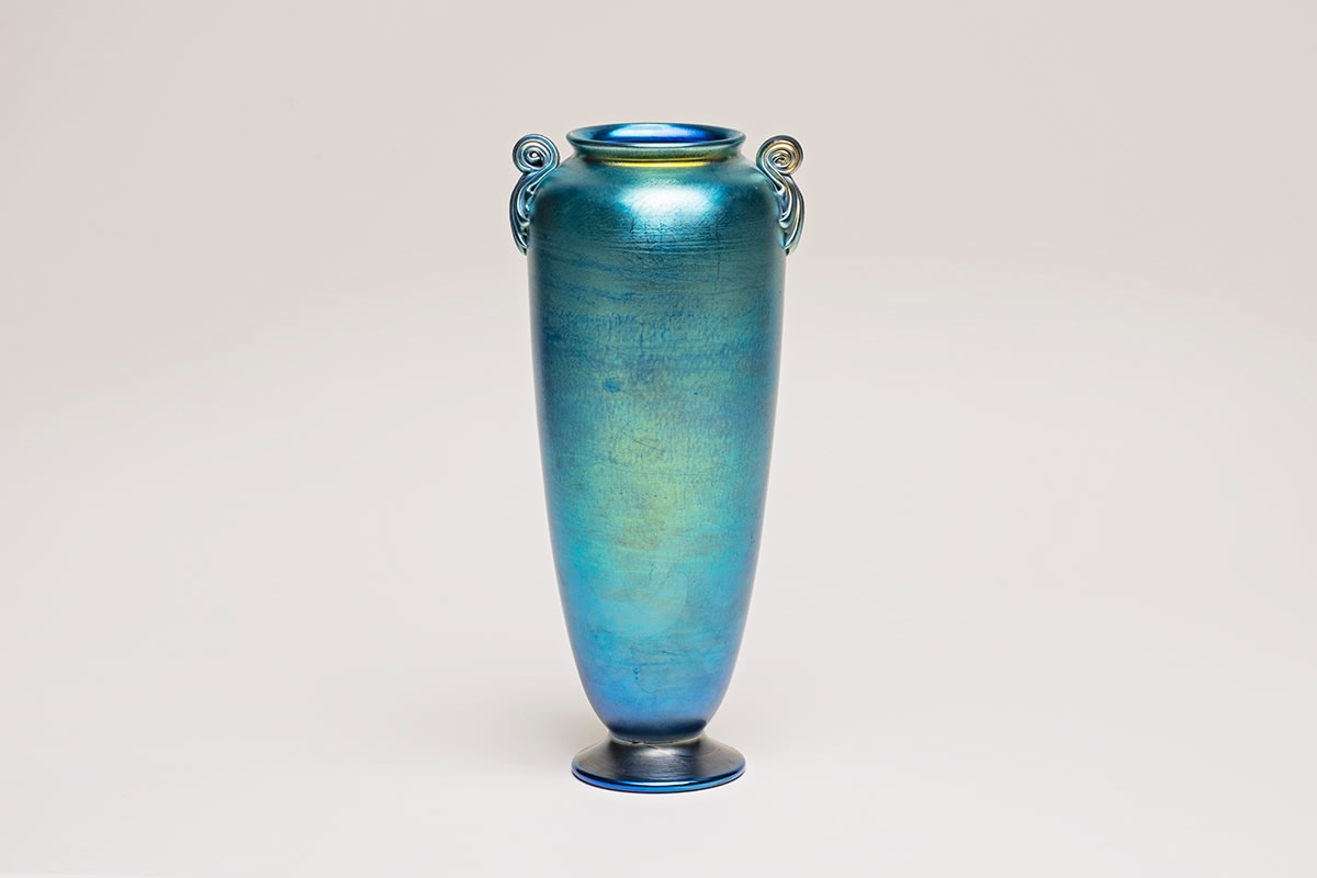 an authentic blown Tiffany Favrile Glass vase of classical footed form, with two small applied scroll handles at the shoulder, formed entirely of richly pigmented sky blue iridescent tiffany glass