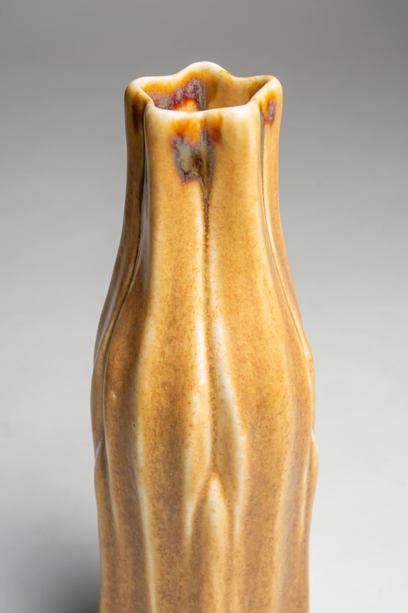 a thin cylindrical vase in the form of stylized overlapping thin leaves, in a speckled yellow glaze, a rare piece of favrile pottery by tiffany studios dating from around 1910