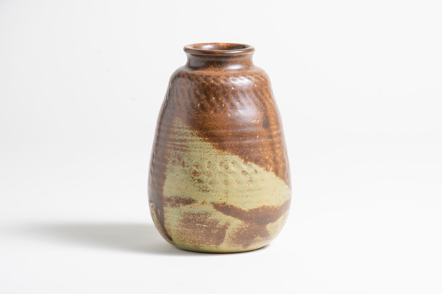 a vase glazed in tan and medium brown, the body with horizontal rows of impressed geometric design including vertical, horizontal, diagonal lines and circular impressions