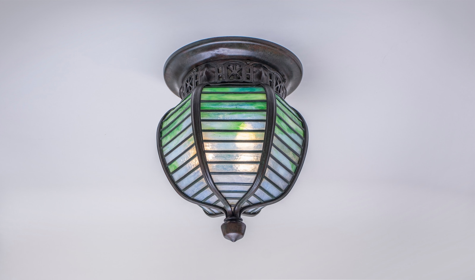 a leaded glass ceiling fixture in the moorish taste by tiffany studios, the shade in leaded green-blue glass with thick vertical ribs, flush mount to the ceiling