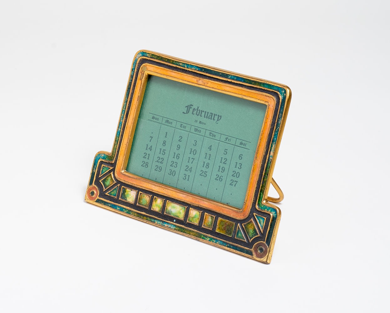 a rectangular calendar frame in gilt bronze, with squared recesses filled with inset enamel in variegated shades of green