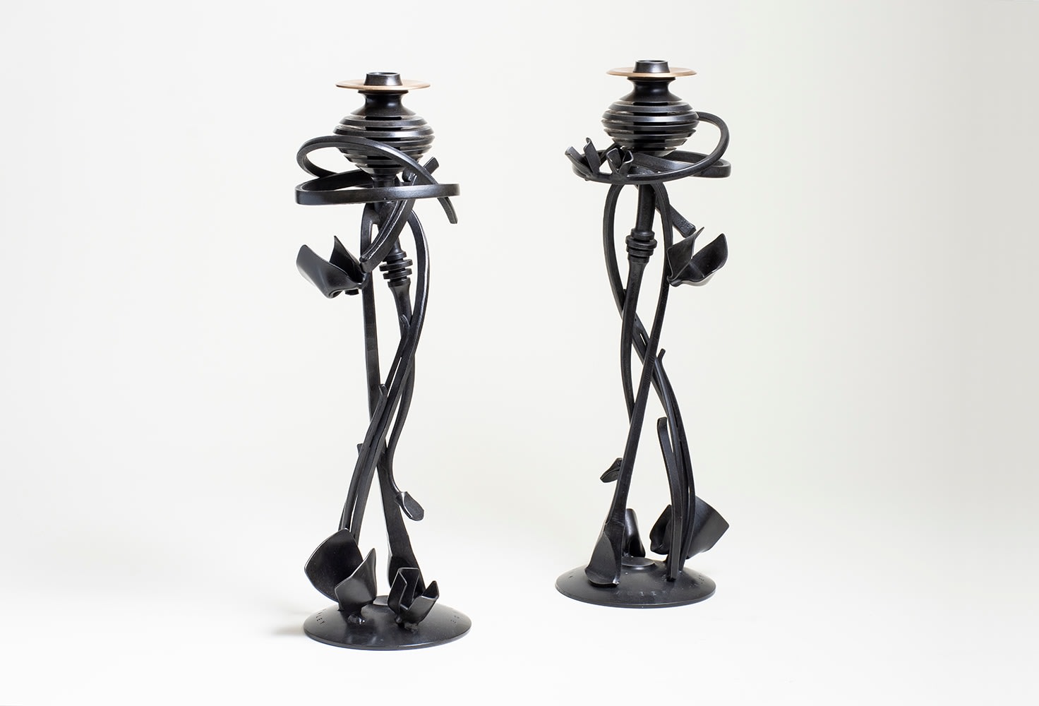 a pair of forged steel candlesticks by albert paley, the central stem surrounded by spirals of thin bands of steel referencing comets