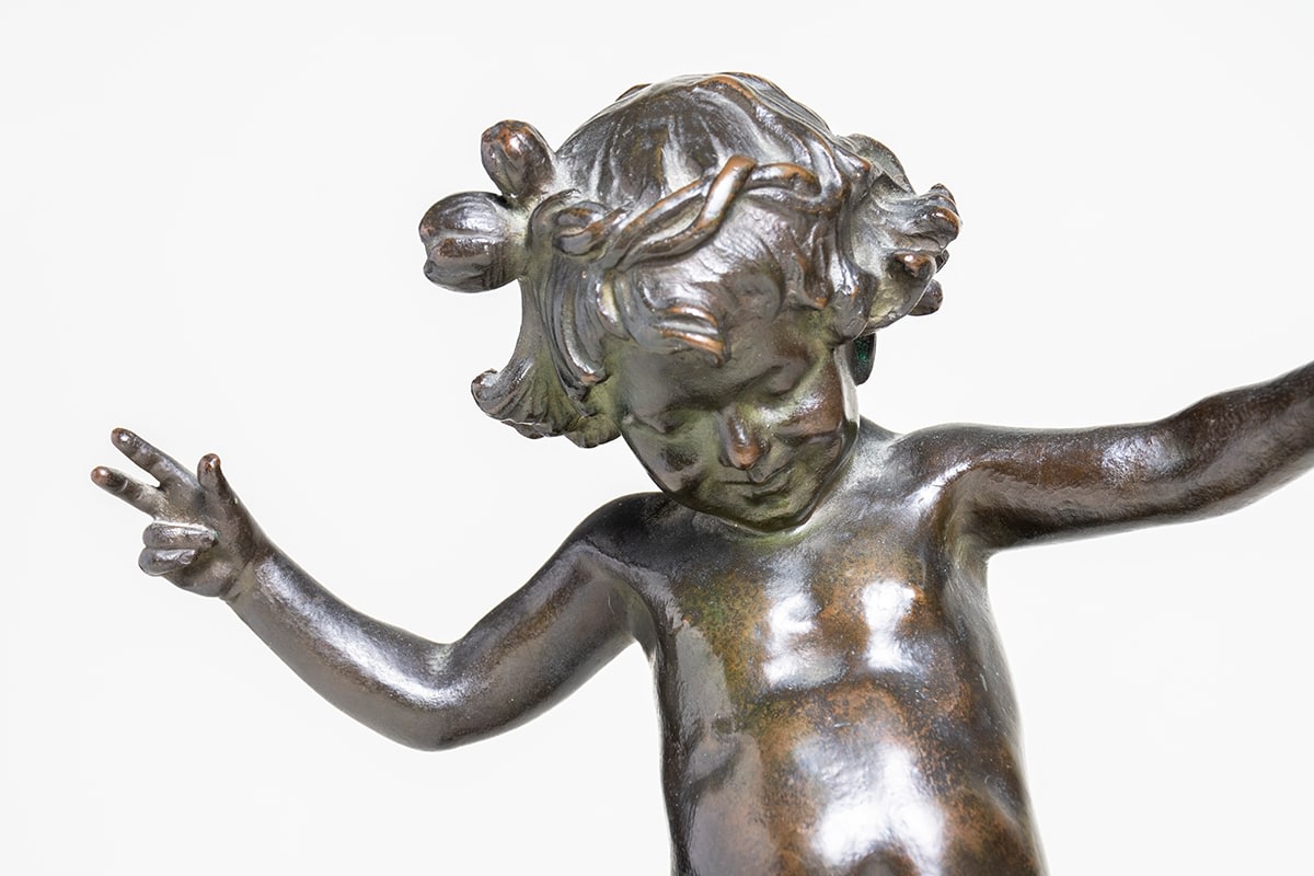 a detail of the face and outstretched arms of the small frolicking child in the center of the fountain called &quot;frog fountain&quot;by janet scudder, the child with a joyous expression and flower fashioned as a cap.