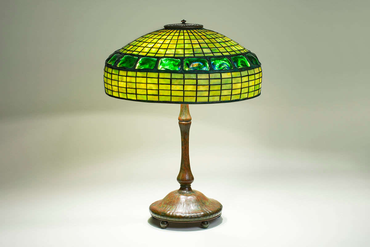 An original leaded glass Tiffany Lamp, the shade subtly domed with straight sides, formed by a grid of mottled green tiffany glass, bisected at the center with a horizontal row of pressed tiffany glass &quot;turtle back&quot; tiles with irregular surfaces and rainbow iridescence