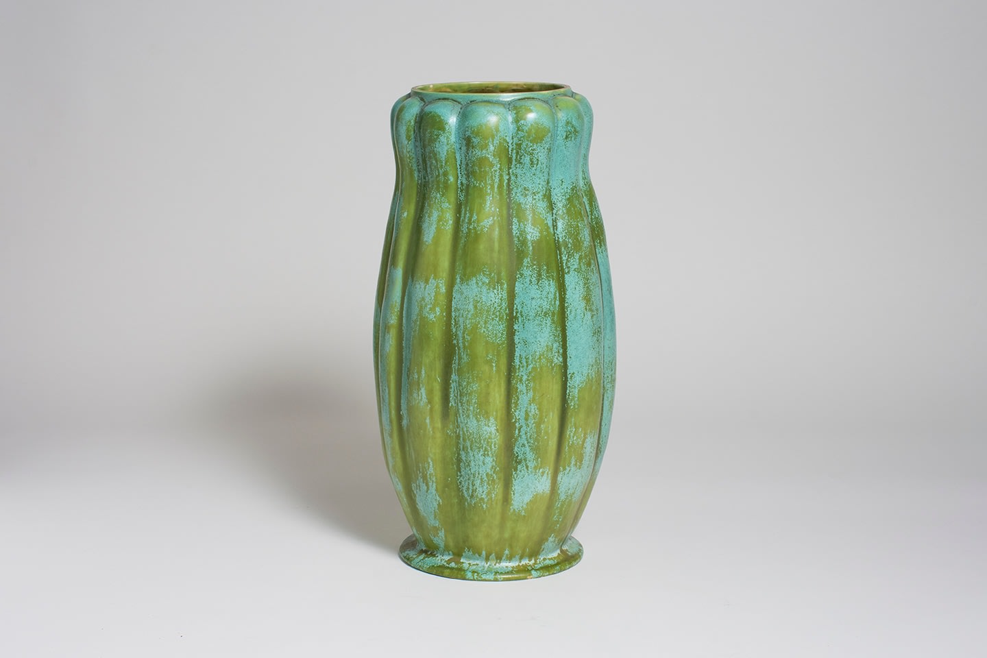a monumental tiffany favrile pottery vase in variegated green glaze, the cylindrical form slightly bulging at the center, with allover convex vertical ribbing