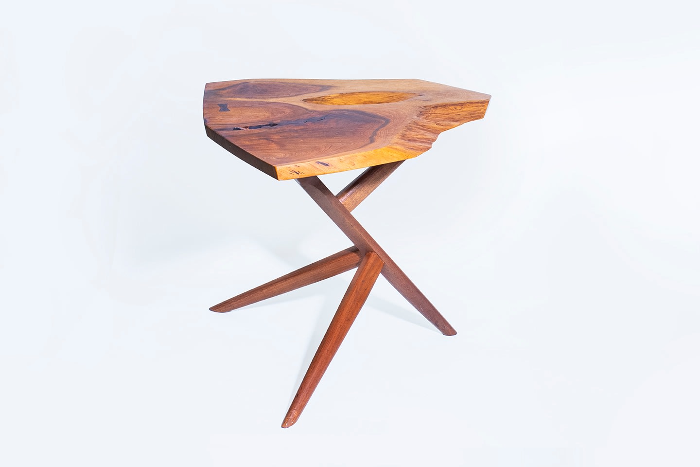 a full shot of a george nakashima conoid side table with american black walnut live edge slab top with highly figured grain, with unusual cross-legged base