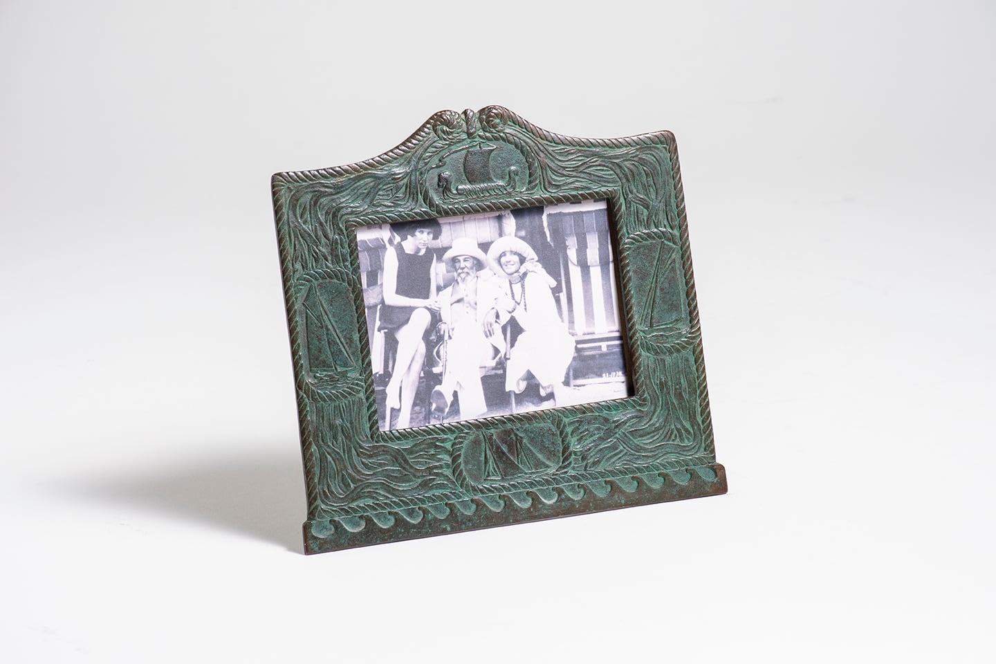 a low rectangular calendar frame from tiffany studios &quot;nautical&quot; desk set, the bronze in a green patina, the frame borders depicting maritime motifs including kelp, rope, and depictions of various sailing ships