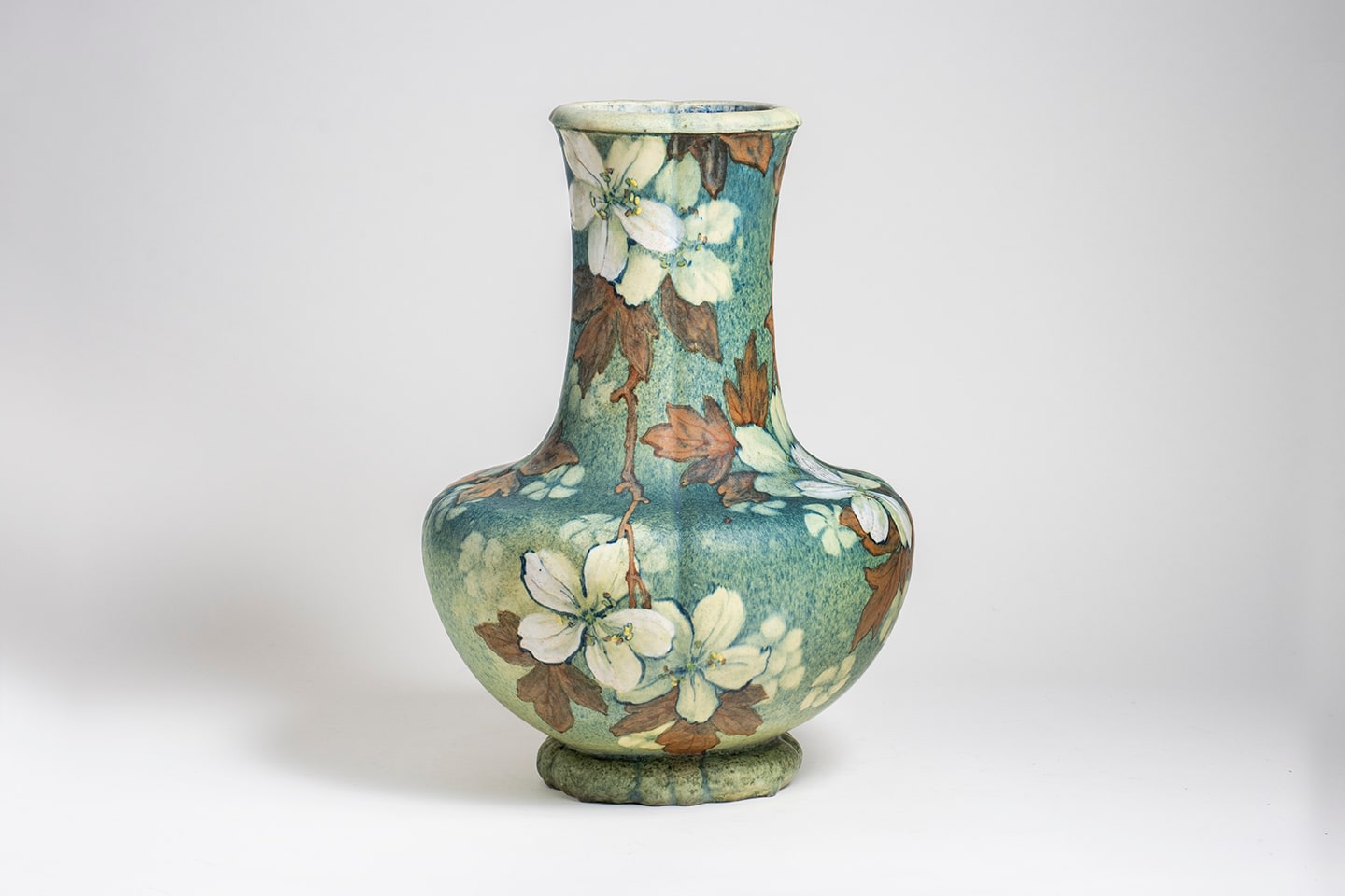 a monumental glazed stoneware vase of baluster form with foot, the body in a matte speckled blue-green glaze with overall motif of white hawthorn blossoms and green-brown leaves