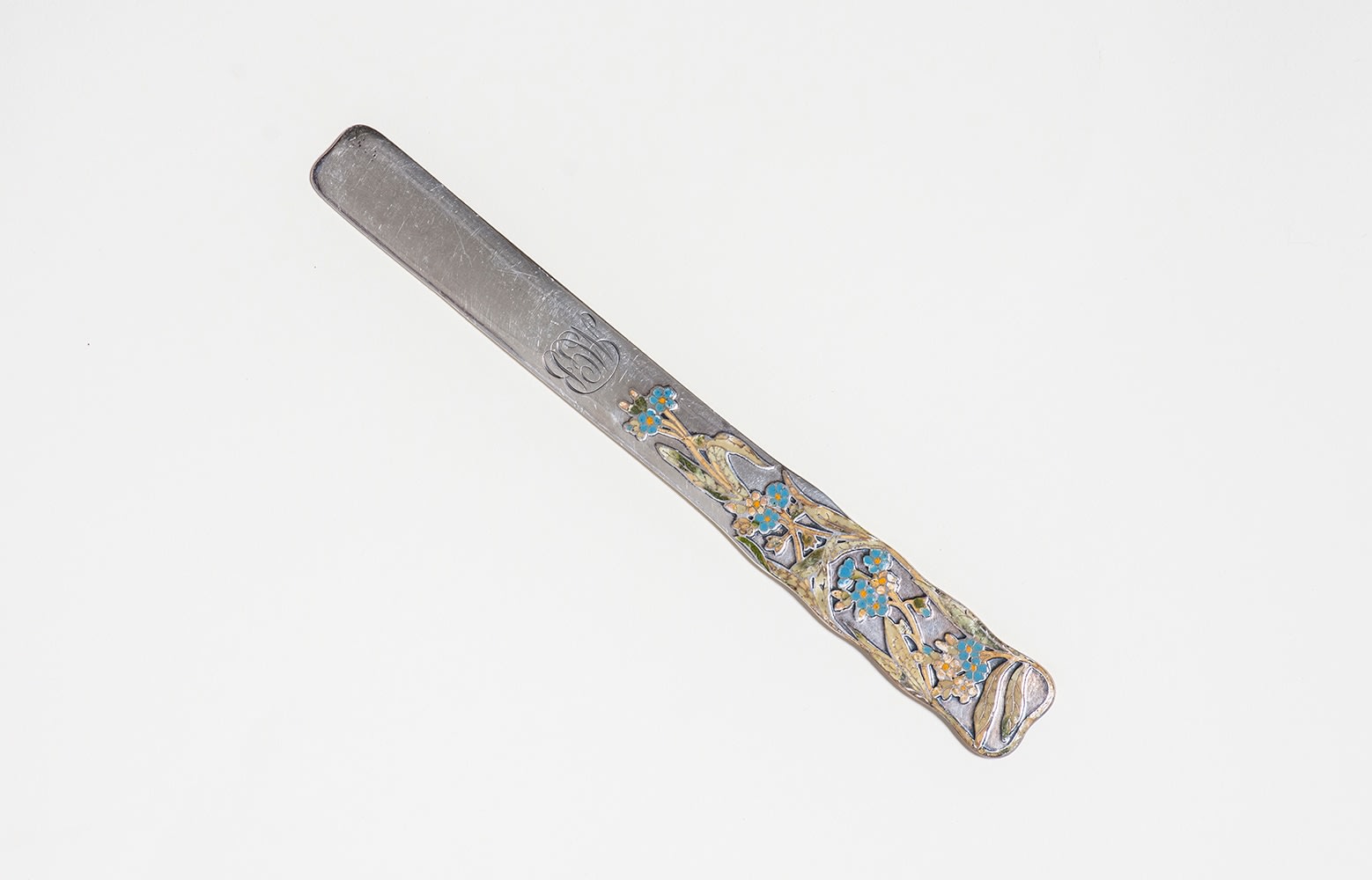a sterling silver paper knife with squared edges, the handle decorated with a cloisonn&eacute; decoration of blue five-petaled flowers with variegated green leaves
